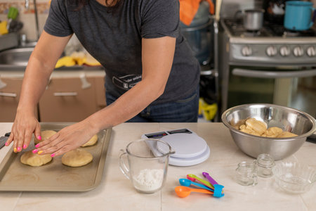 Unrecognizable woman arranges in a tray bread of the dead, which she is preparing in her kitchen