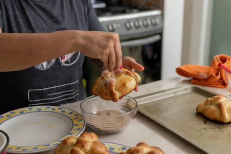 woman putting sugar on a freshly baked bread of the dead at homeの写真素材
