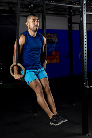 Vertical shot of a gymnast doing ring dips in the haros of a gym
