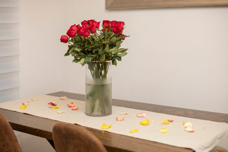 A bouquet of roses in a vase that is on a table in the houseの写真素材