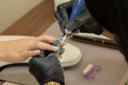 Close-up of a womans nails being polished with a manicure machineの写真素材