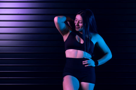 Strong female athlete showing off her physique under neon lights