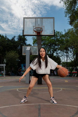 Young woman playing basketball on outdoor courtの写真素材