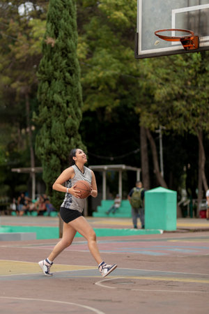 Young latin sportswoman throwing basketball into the hoop in a parkの写真素材