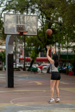 Young woman shooting a basketball in a public parkの写真素材