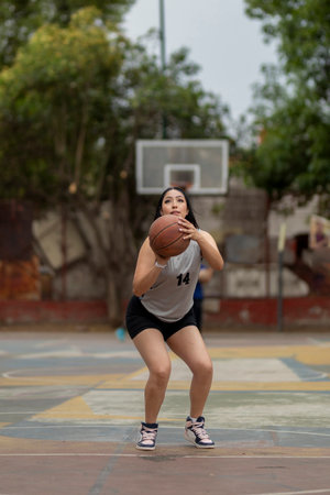 Female basketball player shooting ball on outdoor courtの写真素材