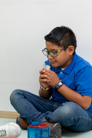Young boy using inhaler for respiratory therapy at homeの写真素材