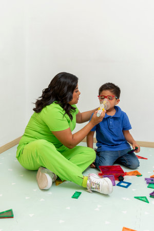 Respiratory therapist assisting child using nebulizer for breathing treatmentの写真素材