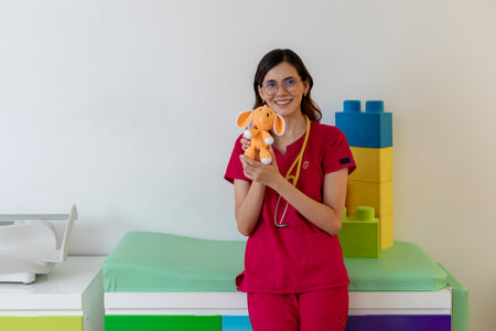 Young pediatrician holding plush toy in colorful officeの写真素材