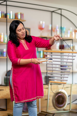 Mexican woman playing bar chimes in music studio for sound healingの写真素材