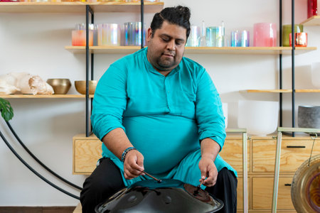 Musician playing handpan in music studio with tibetan singing bowlsの写真素材