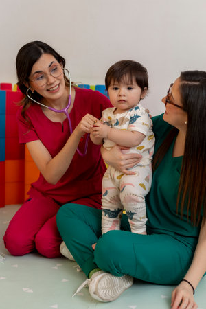 Pediatricians examining baby girl with stethoscope in clinic