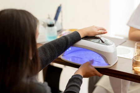 Beautician curing customer nails with uv lamp in beauty salonの写真素材