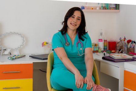 Pediatrician smiling and sitting in her colorful officeの写真素材