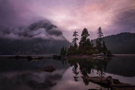 Beautiful morning landscape view on a reflection in the water with an island surrounded by mountains. Picture taken North of Vancouver in Widgeon Lake, British Columbia, Canada, during a cloudy sunrise.の写真素材