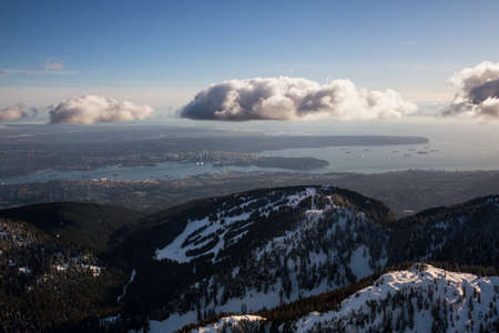 Aerial view of Grouse Mountain and Vancouver Downtown City, BC, Canada, in the background. Picture taken during a cloudy winter sunset.の写真素材