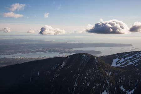 Aerial view of Grouse Mountain and Vancouver Downtown City, BC, Canada, in the background. Picture taken during a cloudy winter sunset.の写真素材