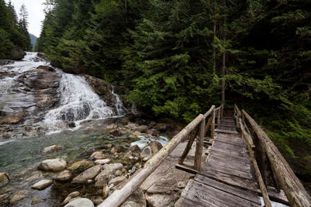 Wooden bridge over a flowing river on a hiking trail. Picture taken on a path to Widgeon Lake near Vancouver, British Columbia, Canada.の写真素材