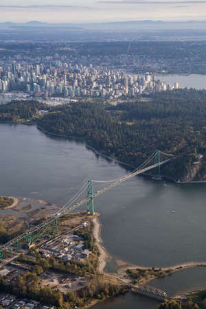 Aerial view on Lions Gate Bridge, Stanley Park, and Downtown Vancouver, during a sunny day.