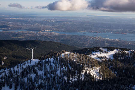 Aerial view of Grouse Mountain and Vancouver Downtown City, BC, Canada, in the background. Picture taken during a cloudy winter sunset.の写真素材