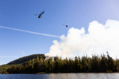 Helicopter fighting BC forest fires during a hot sunny summer day. Taken near Port Alice, Northern Vancouver Island, British Columbia, Canada.の写真素材