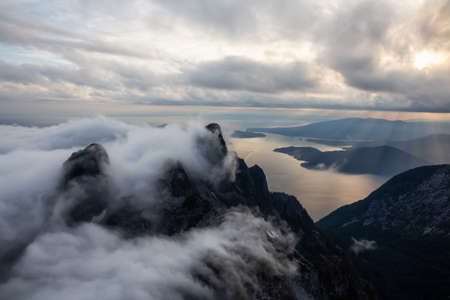 Aerial view of Canadian Mountain Landscape covered in clouds during a vibrant summer sunset. Taken near Vancouver, BC, Canada.の写真素材