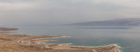 Beautiful aerial panoramic view of a mountain desert landscape and dead sea during a cloudy and sunny day. Taken near Masada National Park, Israel.の写真素材