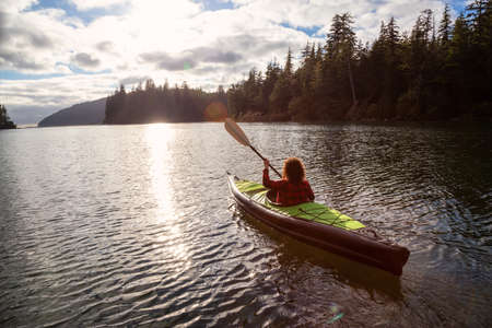 Girl kayaking in a river near the Pacific Ocean during a cloudy summer evening. Taken in San Josef Bay, Cape Scott, Northern Vancouver Island, BC, Canada.の写真素材