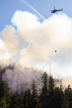 Helicopter fighting BC forest fires during a hot sunny summer day. Taken near Port Alice, Northern Vancouver Island, British Columbia, Canada.の写真素材