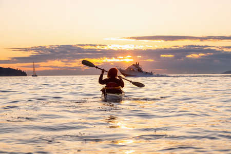 Girl Sea Kayaking during a vibrant sunny summer sunset. Taken in Vancouver, BC, Canada.