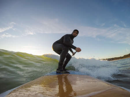 Adventurous Man Surfer on a paddle board is surfing in the ocean during a sunny sunset in Fall Season. Taken in Long Beach, Tofino, Vancouver Island, BC, Canada.の写真素材