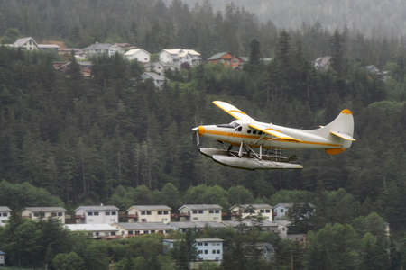 Juneau, Alaska, United States. Floatplane is taking off from water in a small touristic town during a rainy morning.の写真素材