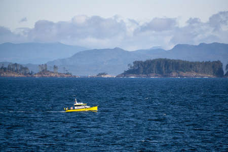 Northern Vancouver Island, British Columbia, Canada - September 27, 2019: Yellow Boat in the Pacific Ocean during a sunny and cloudy day with Islands and the Mainland in the background.のeditorial素材