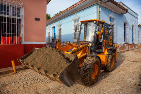 Trinidad, Cuba - June 12, 2019: Male Worker on a Excavator is working in a small Cuban Town during a...