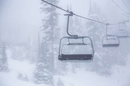 Whistler, British Columbia, Canada. Ski Lift Chairs on the Mountain during a cloudy and foggy winter day.の写真素材