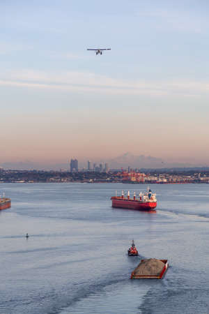 Aerial view of Tugboat, Ship and Airplane in Downtown Vancouver, BC, Canada during a vibrant sunset.の写真素材