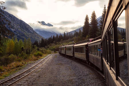 Skagway, Alaska, United States - September 24, 2019: Old Historic Railroad Train is going up White Pass with tourists during a cloudy summer morning.のeditorial素材