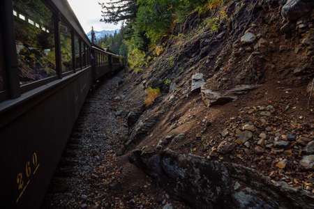 Skagway, Alaska, United States - September 24, 2019: Old Historic Railroad Train is going up White Pass with tourists during a cloudy summer morning.のeditorial素材