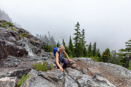 Adventurous Girl is hiking in beautiful green woods in the mountains during a cloudy summer morning....