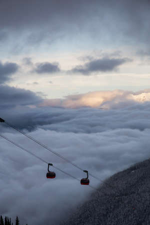 Whistler, British Columbia, Canada. Beautiful View of Peak to Peak Gondola with the Canadian Snow Covered Mountain Landscape during a cloudy and foggy winter day.の写真素材
