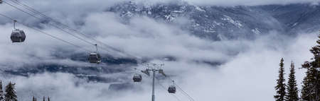 Whistler, British Columbia, Canada. Beautiful View of a Gondola with the Canadian Snow Covered Mountain Landscape during a cloudy and foggy winter day.の写真素材