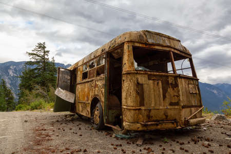 Old, Rusty, Broken and Abandoned Bus on a Dirt Road in the Mountain Valley near a lake during a cloudy summer evening. Taken on Anderson Lake Rd, near Lillooet, BC, Canada.の写真素材