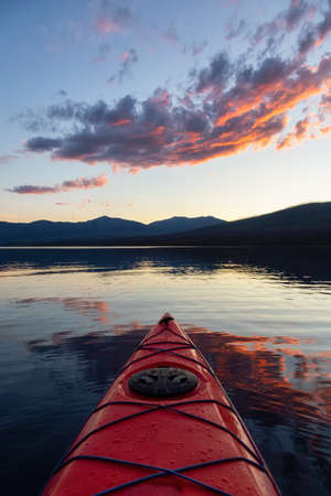 Kayaking in Lake McDonald during a sunny summer sunset with American Rocky Mountains in the background. Taken in Glacier National Park, Montana, USA.の写真素材