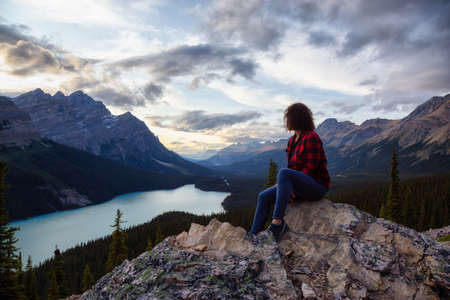 Adventurous girl on the edge of a cliff overlooking the beautiful Canadian Rockies and Peyto Lake...