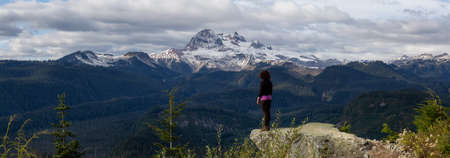 Adventurous Girl near a cliff enjoying the Beautiful Canadian Nature during a colorful and vibrant evening in Fall Season. Taken on a trail to Watersprite Lake near Squamish, North of Vancouver, BC, Canada.の写真素材