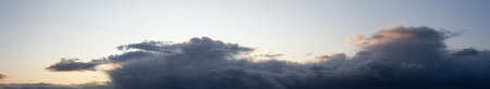 Dramatic Panoramic View of a cloudscape during a dark, rainy and colorful morning sunrise. Taken...
