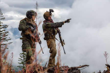Chilliwack, British Columbia, Canada - October 5, 2019: Army Man wearing Tactical Uniform and holding Machine gun in the Outdoor Mountains during fall season.のeditorial素材
