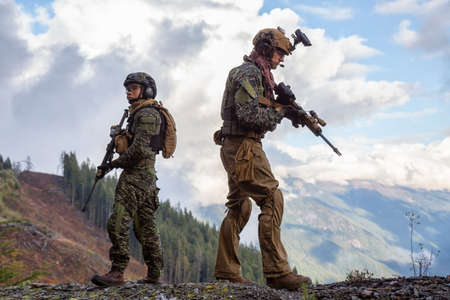 Chilliwack, British Columbia, Canada - October 5, 2019: Army Man wearing Tactical Uniform and holding Machine gun in the Outdoor Mountains during fall season.のeditorial素材