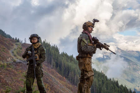 Chilliwack, British Columbia, Canada - October 5, 2019: Army Man wearing Tactical Uniform and holding Machine gun in the Outdoor Mountains during fall season.のeditorial素材