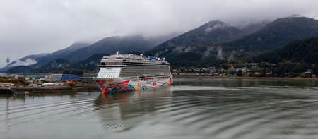 Juneau, Alaska, United States of America - September 23, 2019: Beautiful Panoramic view of a Cruise Ship parked at a small touristic town during a cloudy summer morning.のeditorial素材